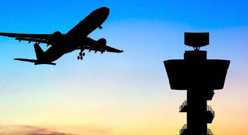 Plane in sky near air traffic control tower